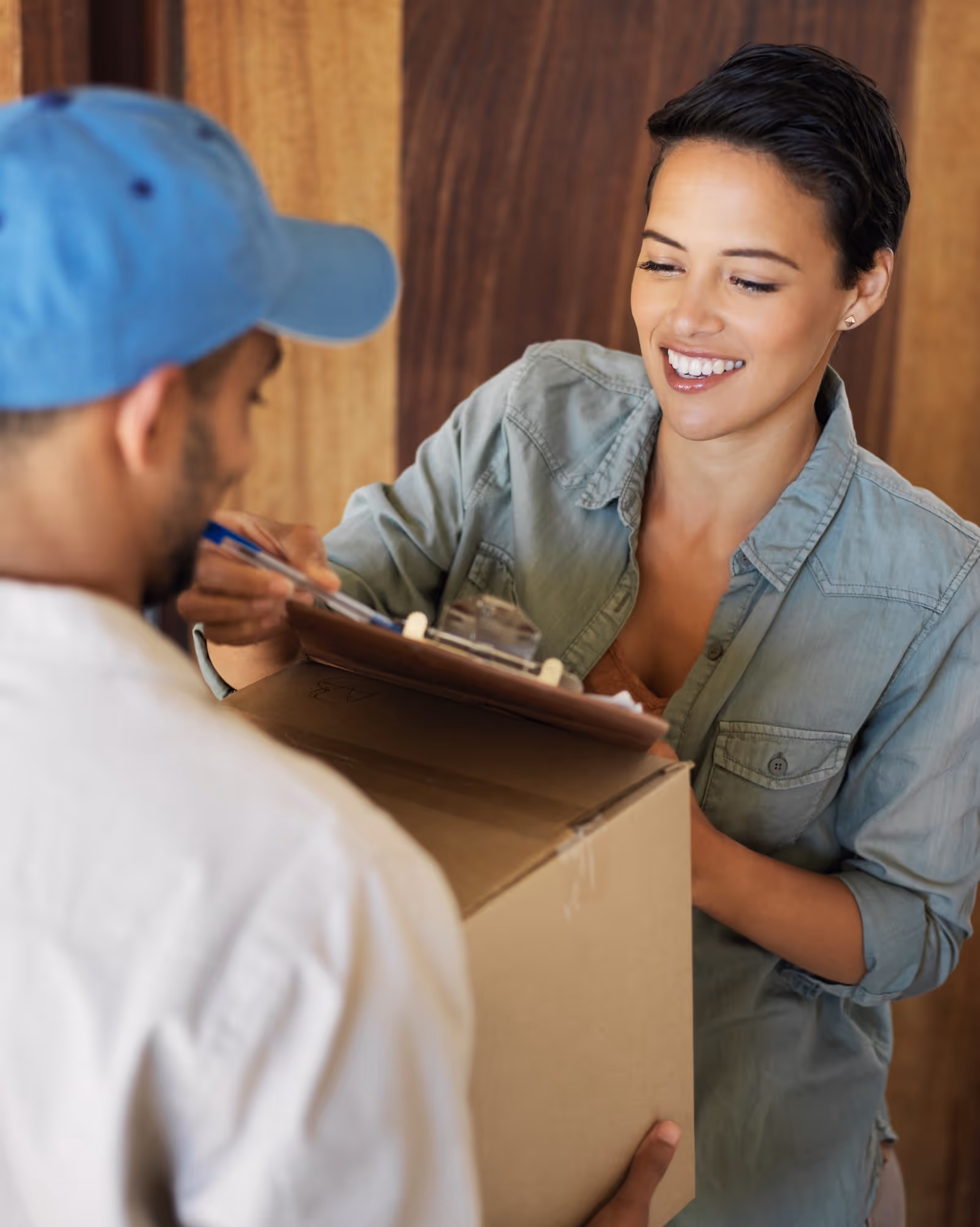 Smiling worker accepting package from delivery person with clipboard